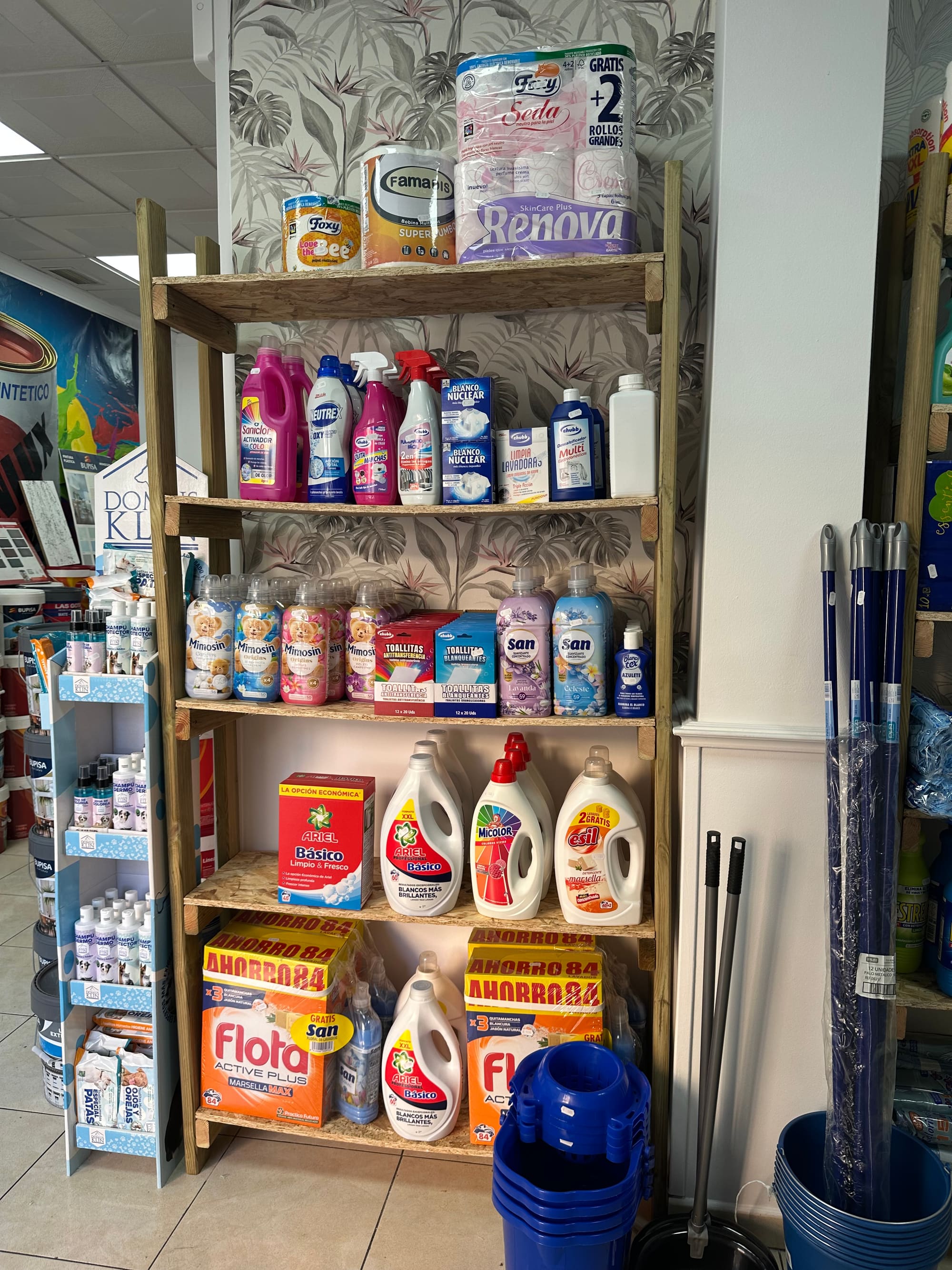 Estantería de droguería con detergentes, suavizantes y cajas de detergente en polvo.